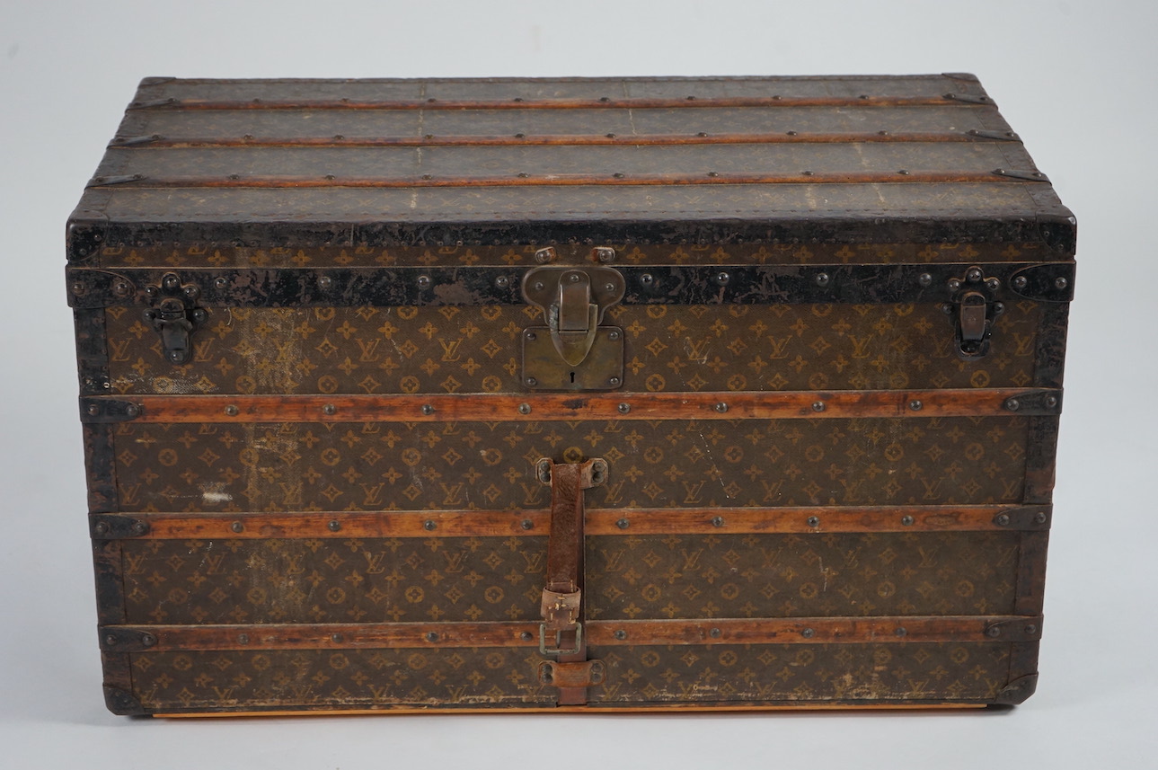 A vintage Louis Vuitton trunk, with wooden slats and black painted steel bound LV canvas, label for Paris, Nice, Lille and London, and numbered stamp 212361, with two internal canvas trays, 100cm wide, 54cm deep, 58cm hi